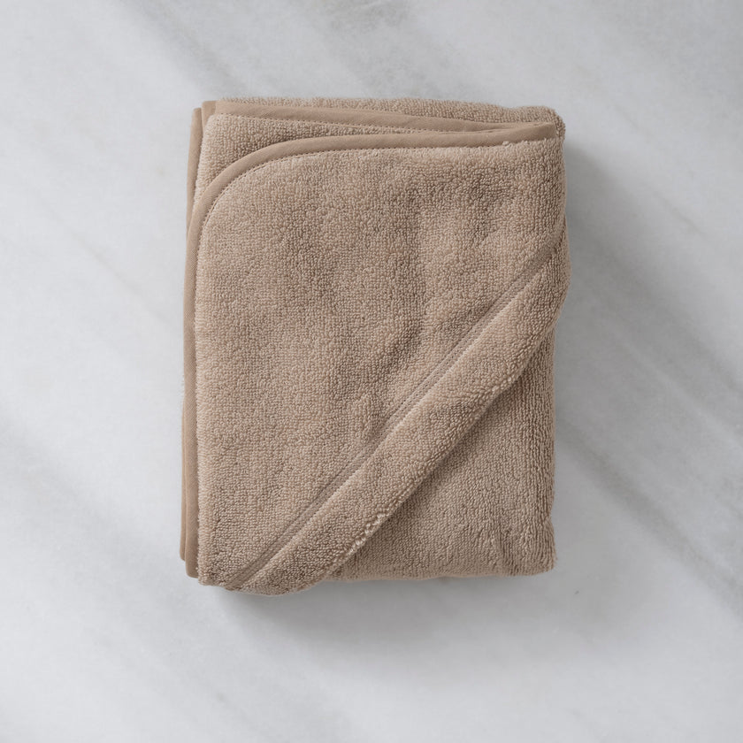 Folded Baby Hooded Towel in color latte, flat lay shot with marble background