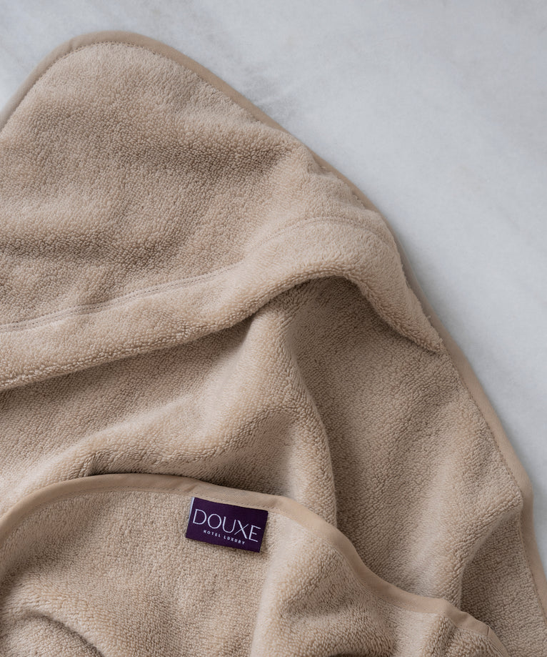 Baby Hooded Towel in color latte, detail shot from hood and DOUXE logo with marble background