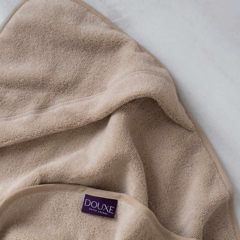 Baby Hooded Towel in color latte, detail shot from hood and DOUXE logo with marble background