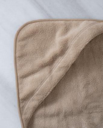 Baby Hooded Towel in color latte, detail shot from hood and DOUXE logo with marble background