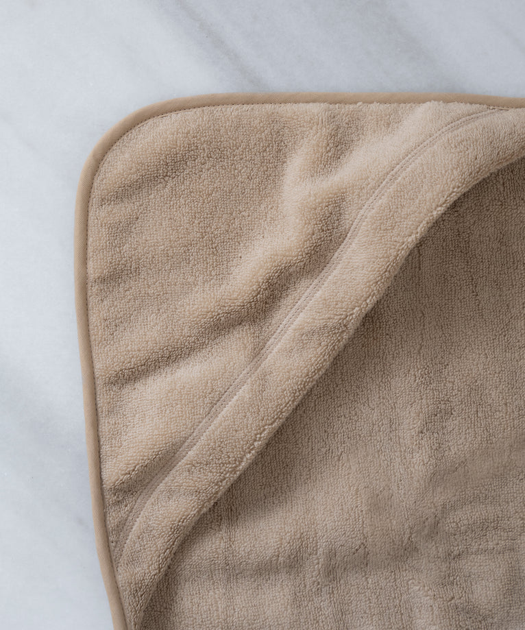 Baby hooded towel in color latte, detail shot from hood with marble background