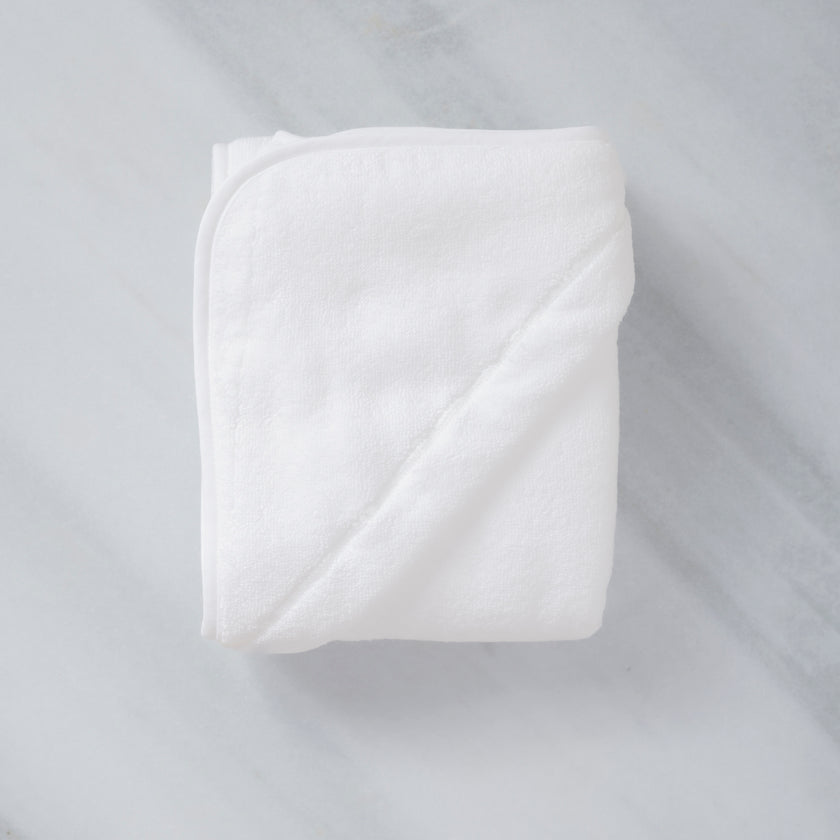 Folded Baby Hooded Towel in white, flat lay shot with marble background