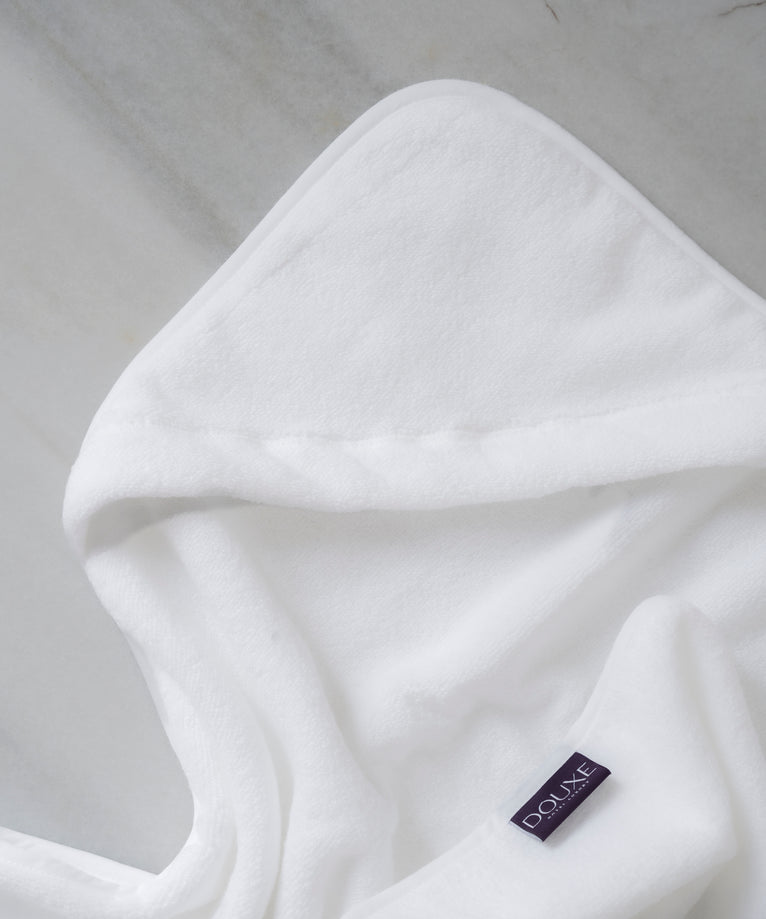 Baby Hooded Towel in white, detail shot from hood and DOUXE logo with marble background