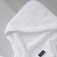 Baby Hooded Towel in white, detail shot from hood and DOUXE logo with marble background