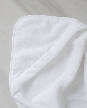 Baby Hooded Towel in white, detail shot from hood and DOUXE logo with marble background