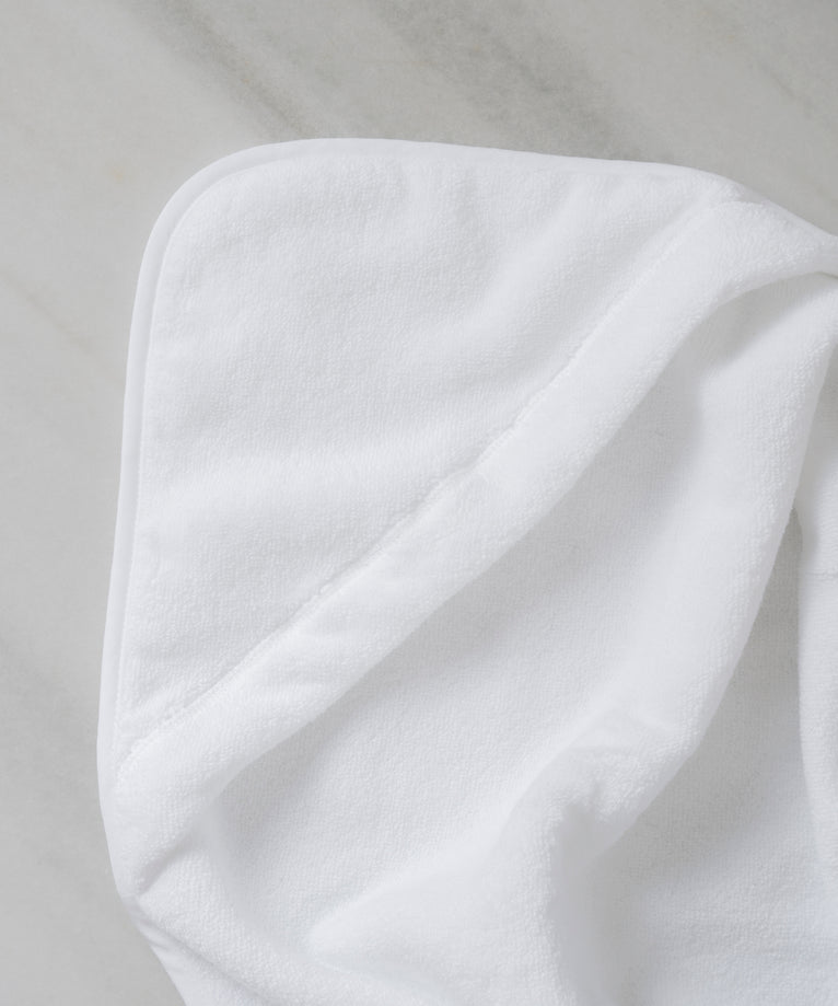 Baby hooded towel in color white, detail shot from hood with marble background