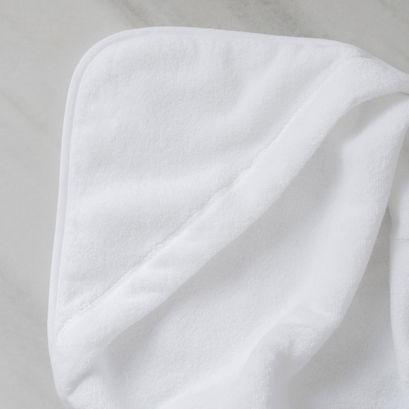 Baby hooded towel in color white, detail shot from hood with marble background