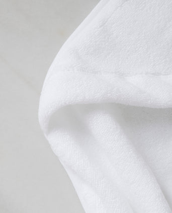 Baby Hooded Towel in white, detail shot from hood and DOUXE logo with marble background