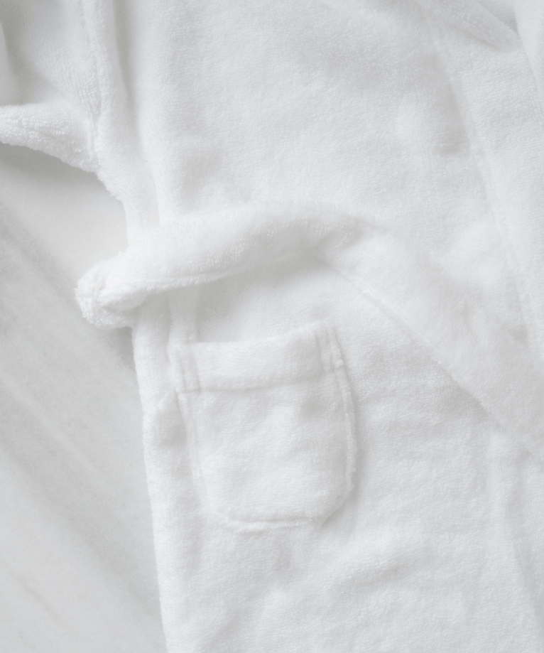 Children's bathrobe in white, detail shot of the patch pocket and tie belt