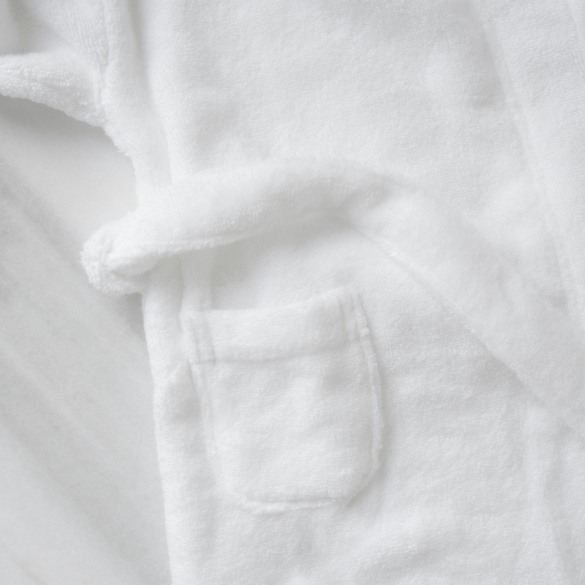 Children's bathrobe in white, detail shot of the patch pocket and tie belt